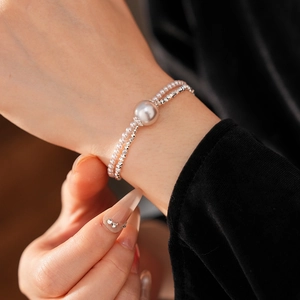 Close-up of a double-layer silver bead bracelet with a central round pearl on wrist
