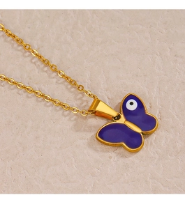 Macro detail of a golden necklace featuring a purple butterfly pendant and evil eye design