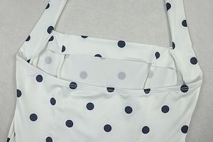Close-up of black polka dots on white fabric with detailed neckline and straps