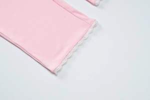 Detail of pink ribbed knit fabric with delicate white lace trim and refined texture
