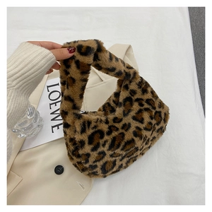 Close-up of fluffy leopard print plush handbag resting on a beige fabric blazer