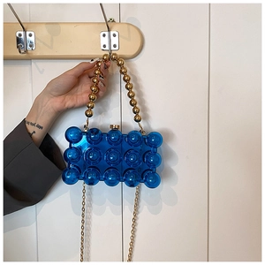 Detail of blue acrylic bubble evening bag with pearl handle and golden chain strap