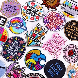 Detailed view of various colorful embroidered patches with creative slogans for clothing