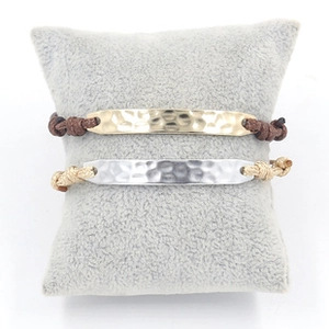 Detail of woven leather bracelets with hammered gold and silver crown charm on display