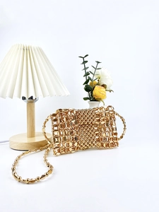 Handcrafted gold woven metal bead crossbody bag with matching chain strap on white background