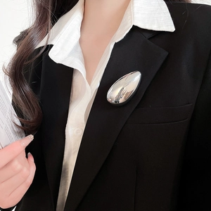 Irregular metal silver brooch on black suit lapel with minimalist droplet design details