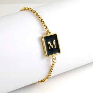 Detailed macro view of 18K gold plated rectangular pendant with black enamel letter M