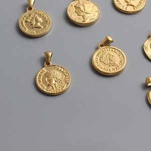 Polished 18K gold plated titanium steel Roman coin pendants on a neutral gray surface