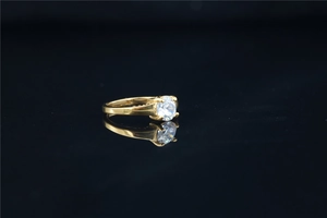 Detailed view of gold titanium ring featuring a four-prong set round moissanite on black