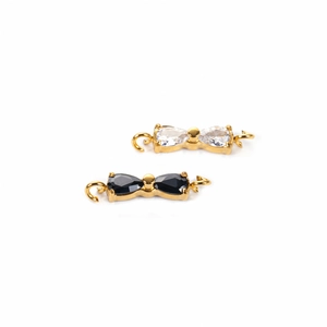 Detail of gold-plated bow charm with white cubic zirconia and black gemstone in high detail