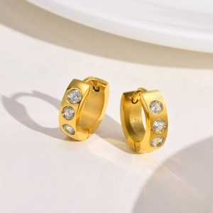 Macro detail of gold-plated stainless steel hoop earrings with three inlaid cubic zirconia