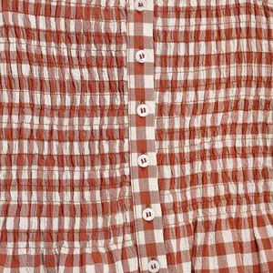 Brown and white checkered smocked crop top with white buttons and pleated texture