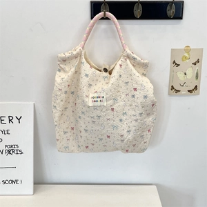 Close-up of quilted cream canvas tote with colorful rabbit patterns and woven rope handles