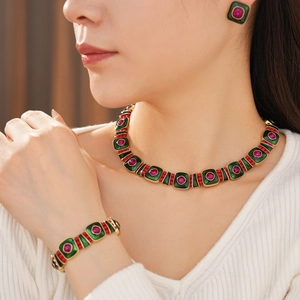 Vintage gold necklace set with green enamel and red gemstones on professional model