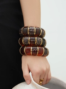 Detailed close-up of leopard print resin bangles with 18k gold accents on a model wrist