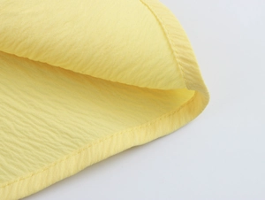 Dettaglio della trama del tessuto giallo e delle cuciture dell'abito a strati