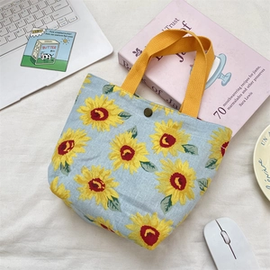 Light blue canvas tote bag with sunflower pattern and yellow handles in a lifestyle setting