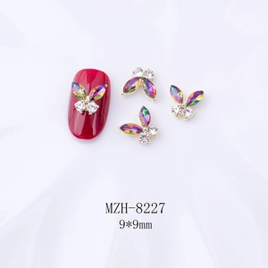 Détail macro du charm ongle papillon 3D avec ailes en cristal et base dorée, 9x9mm