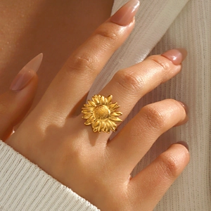 Bague tournesol tendance en acier inoxydable doré portée au doigt avec lumière chaude