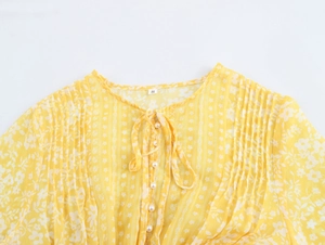 Close-up of yellow floral chiffon dress featuring neck ties and pearlescent buttons