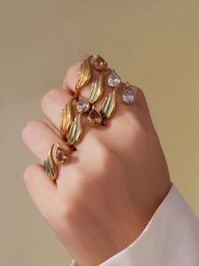 Detail of gold stacking rings featuring blue enamel and pear-cut teardrop gemstones