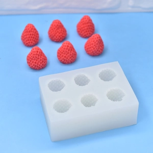 Close-up of 6-cavity silicone mold with finished strawberry soaps on blue background