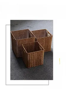 Detail view of woven storage baskets in three sizes with side handles and brown finish