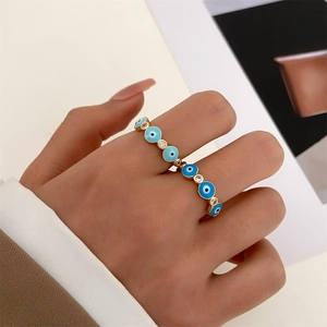 Detail of 14k gold evil eye ring with blue enamel and zircons on woman's hand