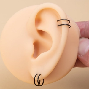 Macro shot of double-layer black stainless steel spiral nose ring on a silicone ear model