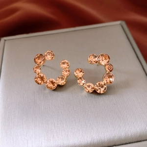 Vue macro de boucles d'oreilles en cristal champagne en forme de C sur un écrin luxe