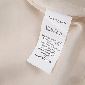 Detail of 100% polyester care label and washing instructions on a beige plush coat