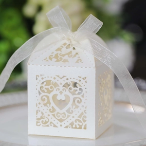 Macro shot of laser-cut heart candy box in white pearl paper with silk ribbon