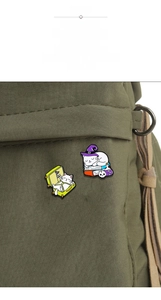 Detail view of two cute magic cat enamel pins attached to a green canvas backpack