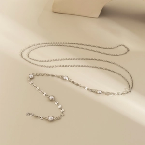 Dettaglio della collana a catena argentata con perle bianche e paillettes metalliche