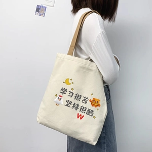 Detail of off-white canvas tote with brown straps and cute cartoon chicken character