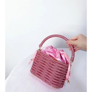 Detailed view of pink rhinestone bucket bag with satin drawstring and pearl charm