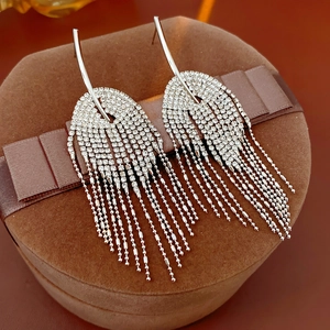 Détail de boucles d'oreilles argentées à pampilles avec pavé de diamants sur écrin