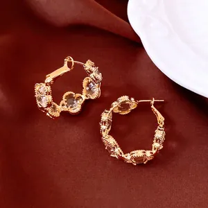 Boucles d'oreilles fleurs plaquées or 18k avec cristaux sur fond en velours rouge foncé