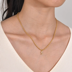 Detail of gold snowflake chain with sparkling diamond letter S pendant for women
