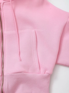 Detail of pink hoodie featuring a sturdy metal zipper and large functional pockets