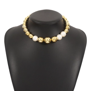 Detail of chunky gold beads and white pearls on a stylish short choker necklace