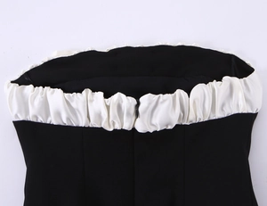 Detail of white ruffled trim on a black bandeau top featuring a hidden back zipper