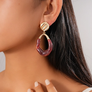 Detail of vintage oval resin earrings with gold pleated metal on a female model