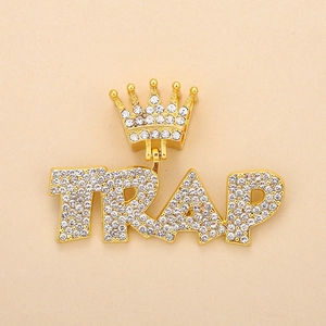 Detail of gold crown and TRAP letter pendant encrusted with diamonds on gold chain