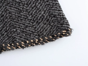 Detailed macro shot of grey woven knit fabric featuring golden sequins and braided edge trim
