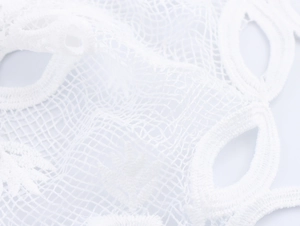 Dettaglio macro del tessuto in pizzo bianco idrosolubile con ricamo floreale elegante