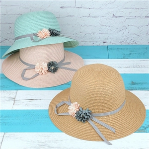 Close-up of woven straw hats featuring 3D floral accents and polka dot ribbon details