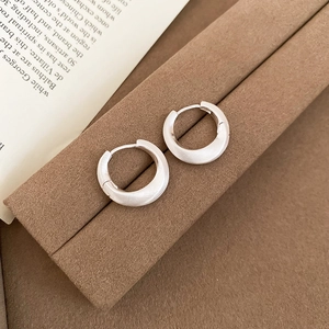 Detailed view of brushed silver hoop earrings on a velvet box with a matte texture finish
