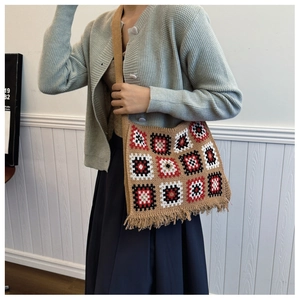 Bohemian knit tote bag with geometric patterns and fringe detail shown on shoulder