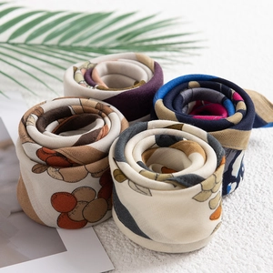Vintage geometric print silk-like scarves in multiple colors rolled on a textured surface